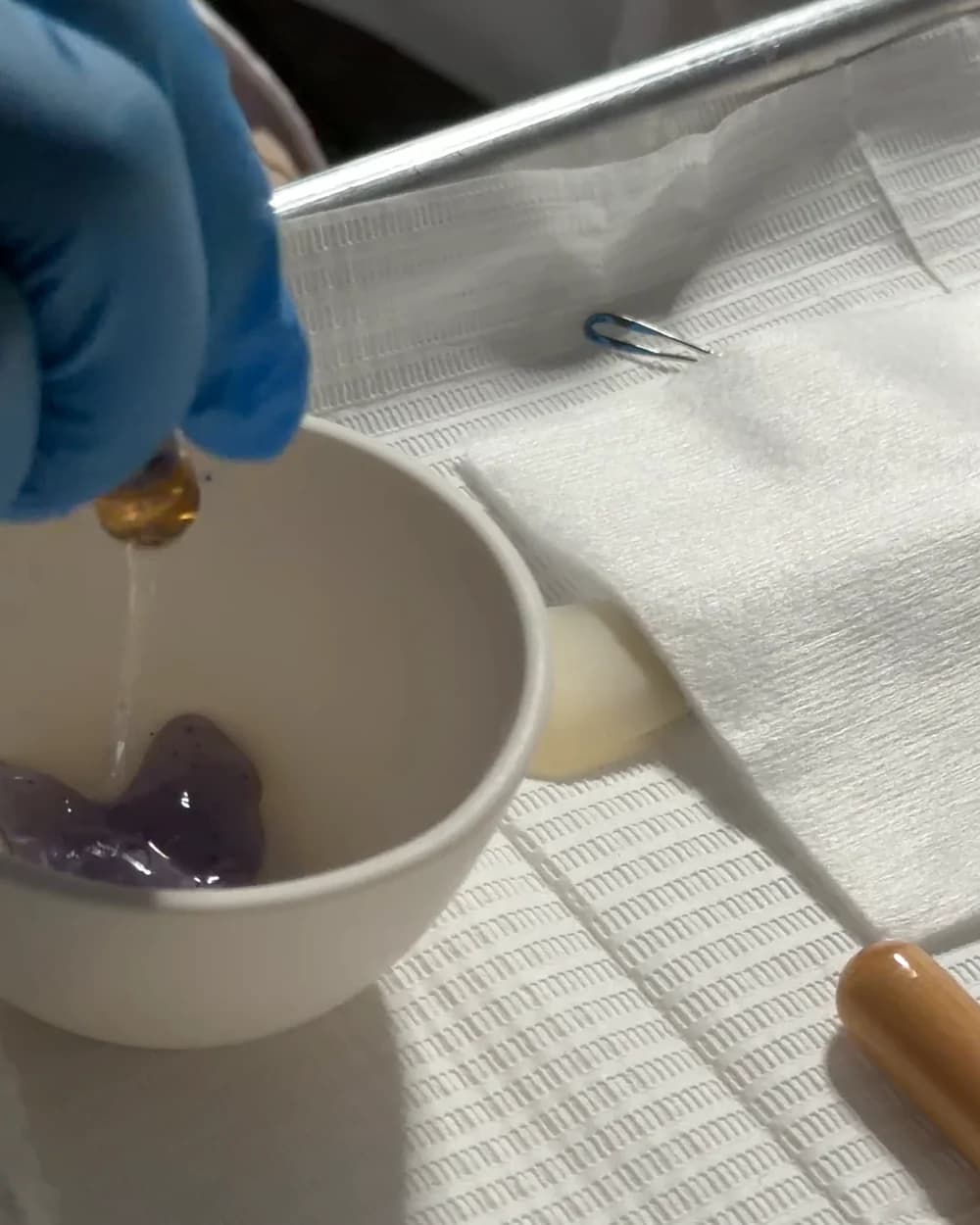 Gloved hands preparing a product in a bowl