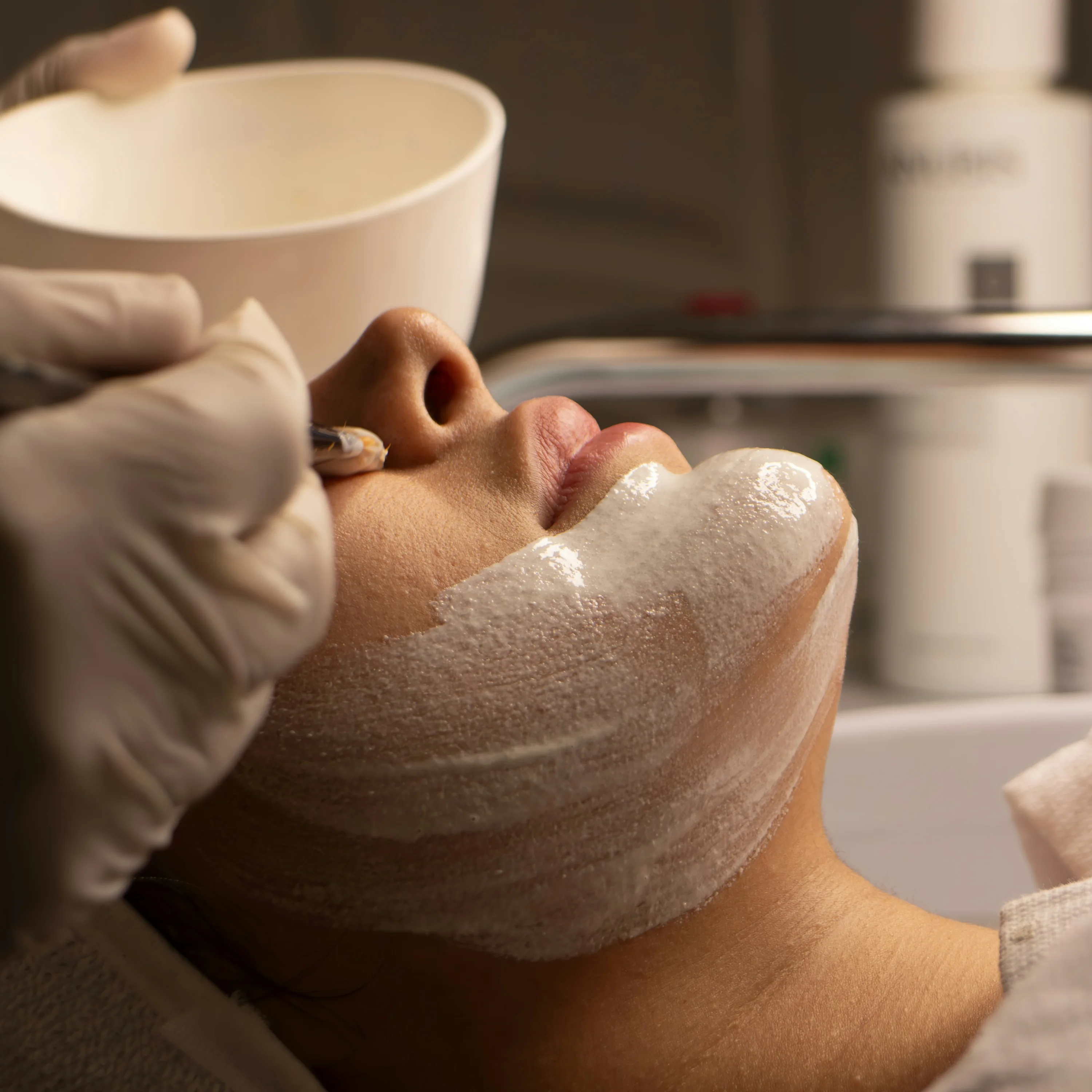 Esthetician applying a facial mask with a brush
